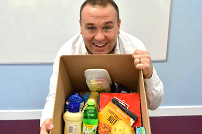 Photo of a smiling client with a box of healthy food.